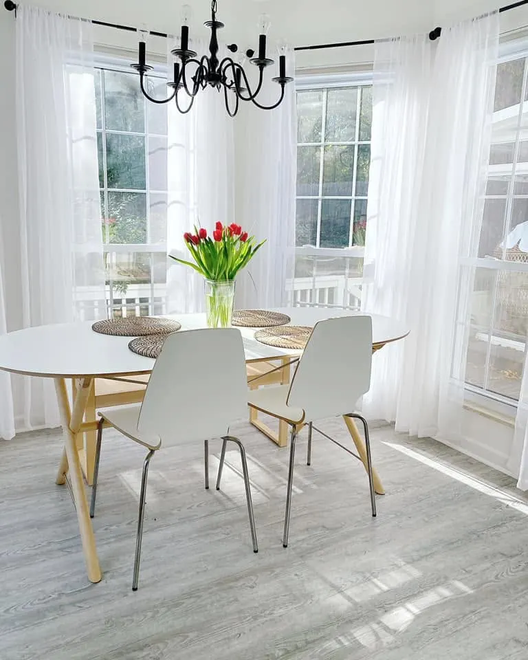 Bright dining nook with gray wood-look plank flooring and bay windows
